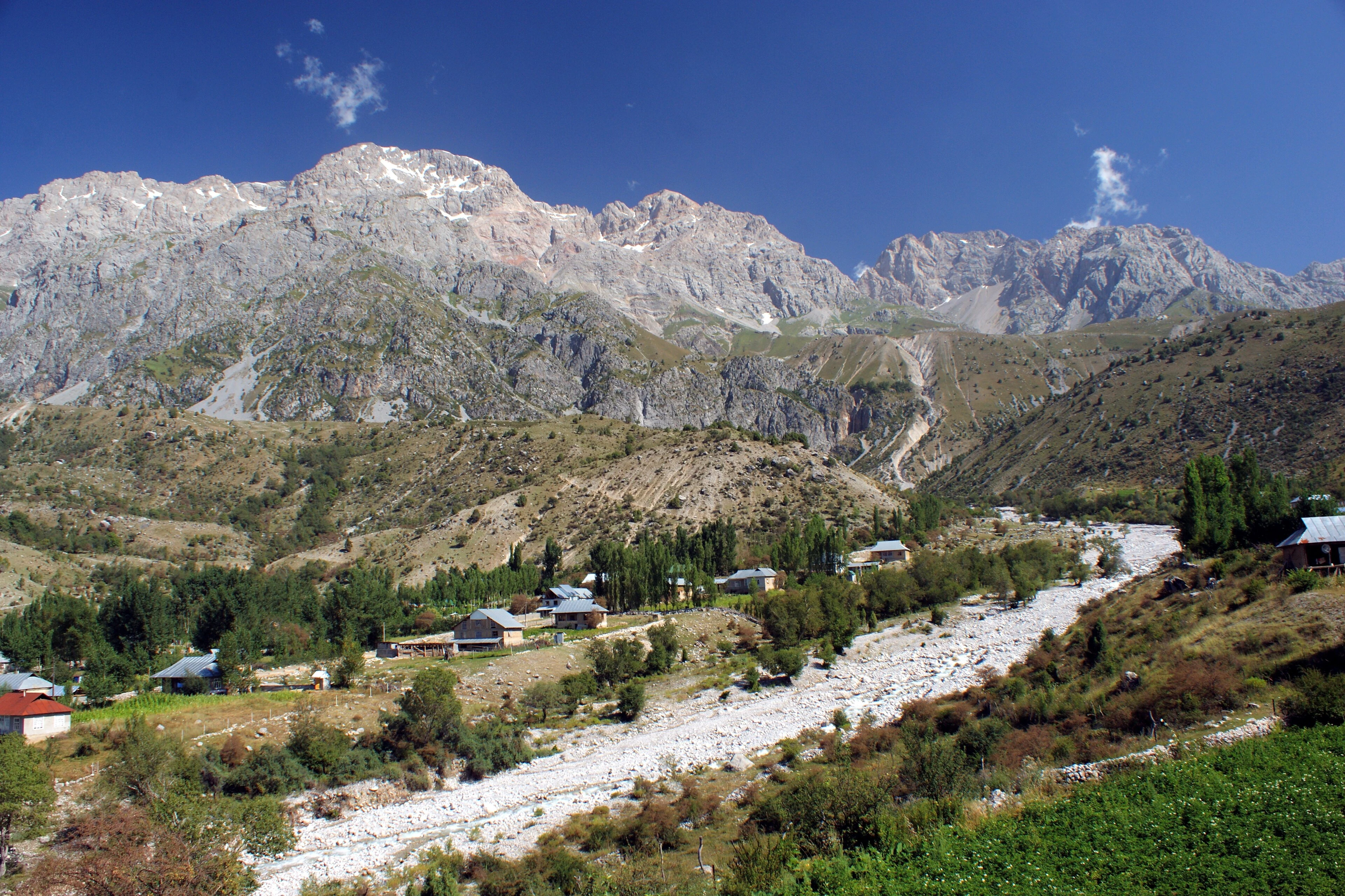 Arslanbob village and river beneath the rocky slopes on the route toward the large waterfall.