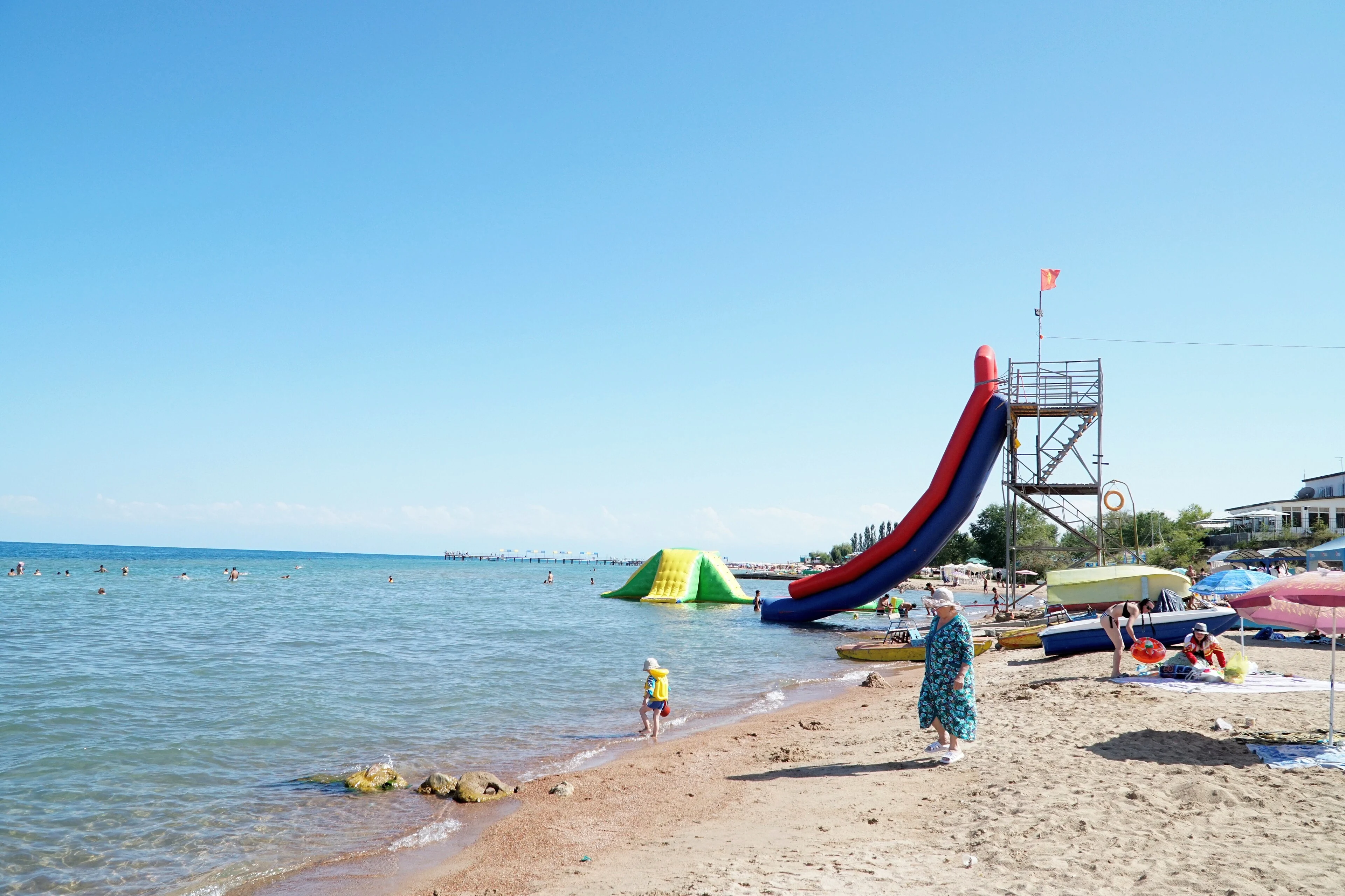 A sunny beach and swimmers on the shore of Issyk-Kul at Cholpon-Ata.