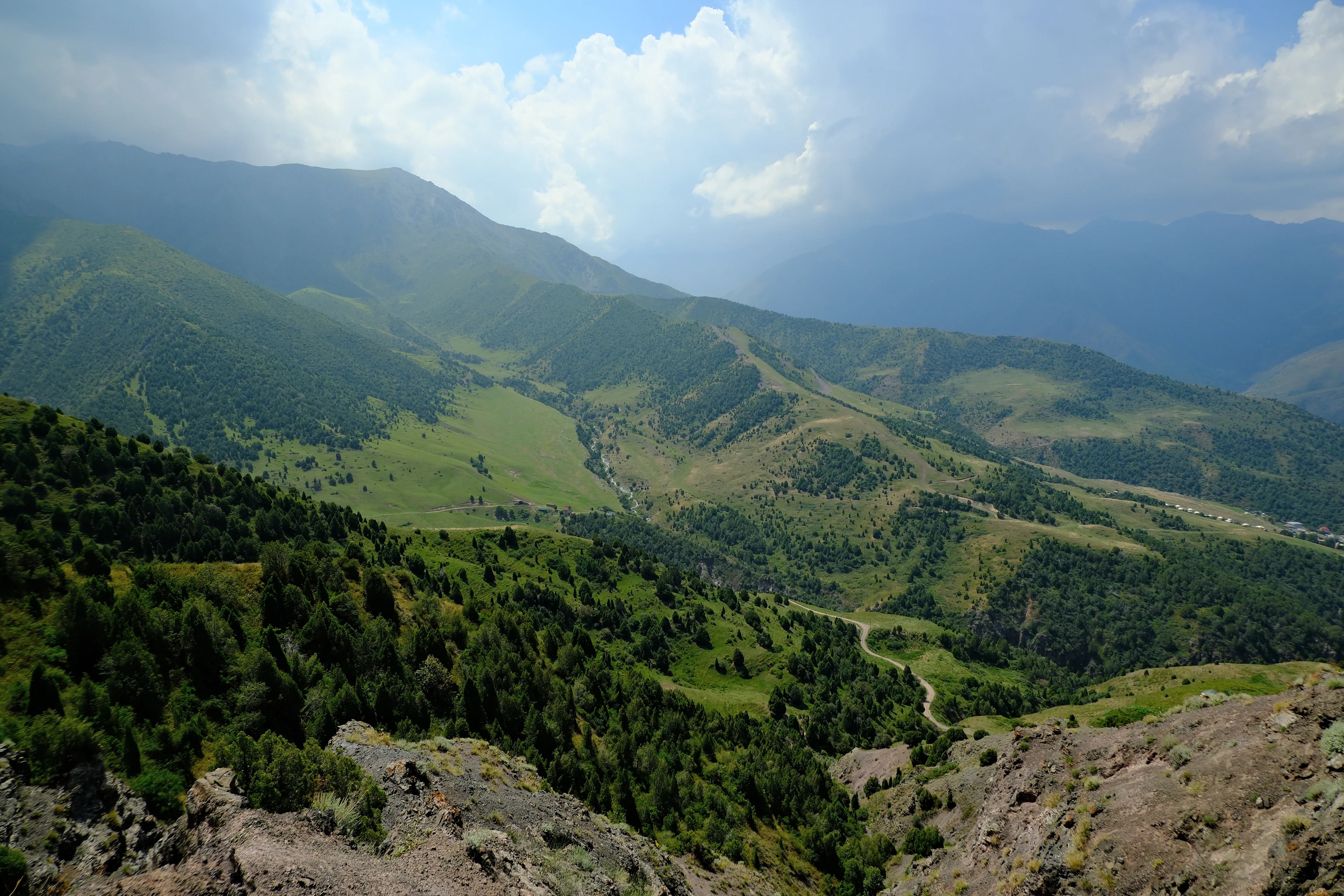 Green ridgelines and open pastures in the Alamedin area.
