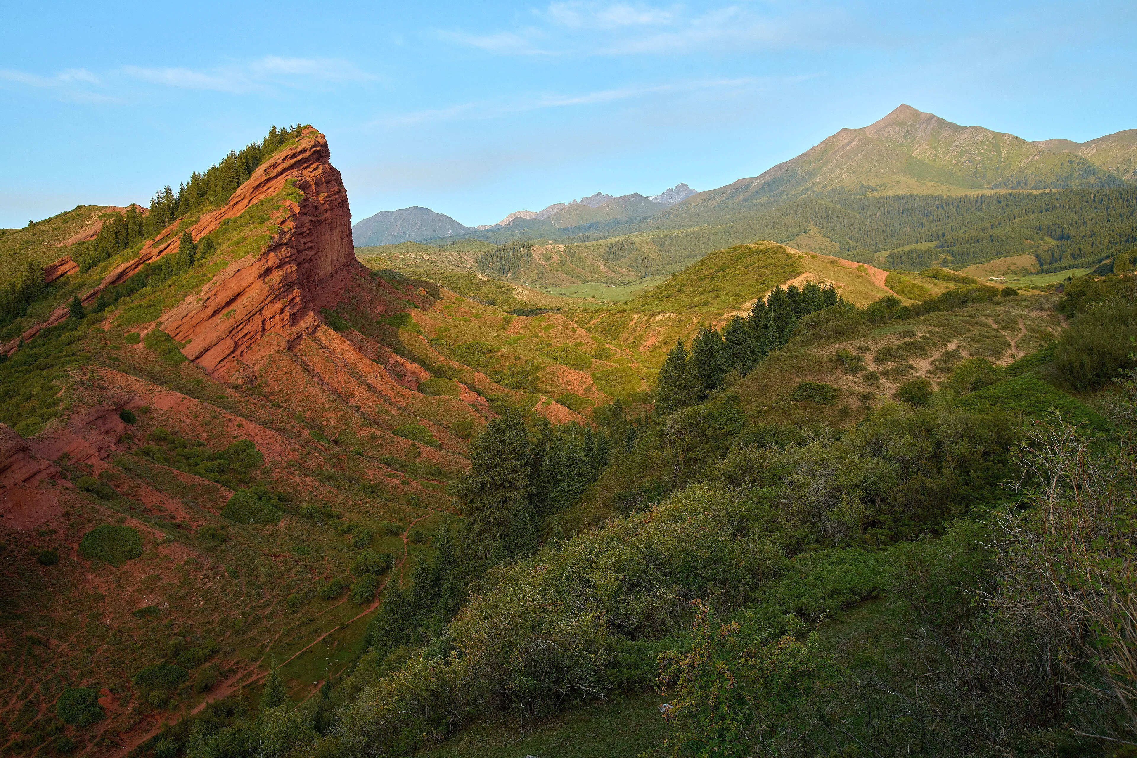 Red sandstone cliffs and green slopes at Jeti-Oguz.