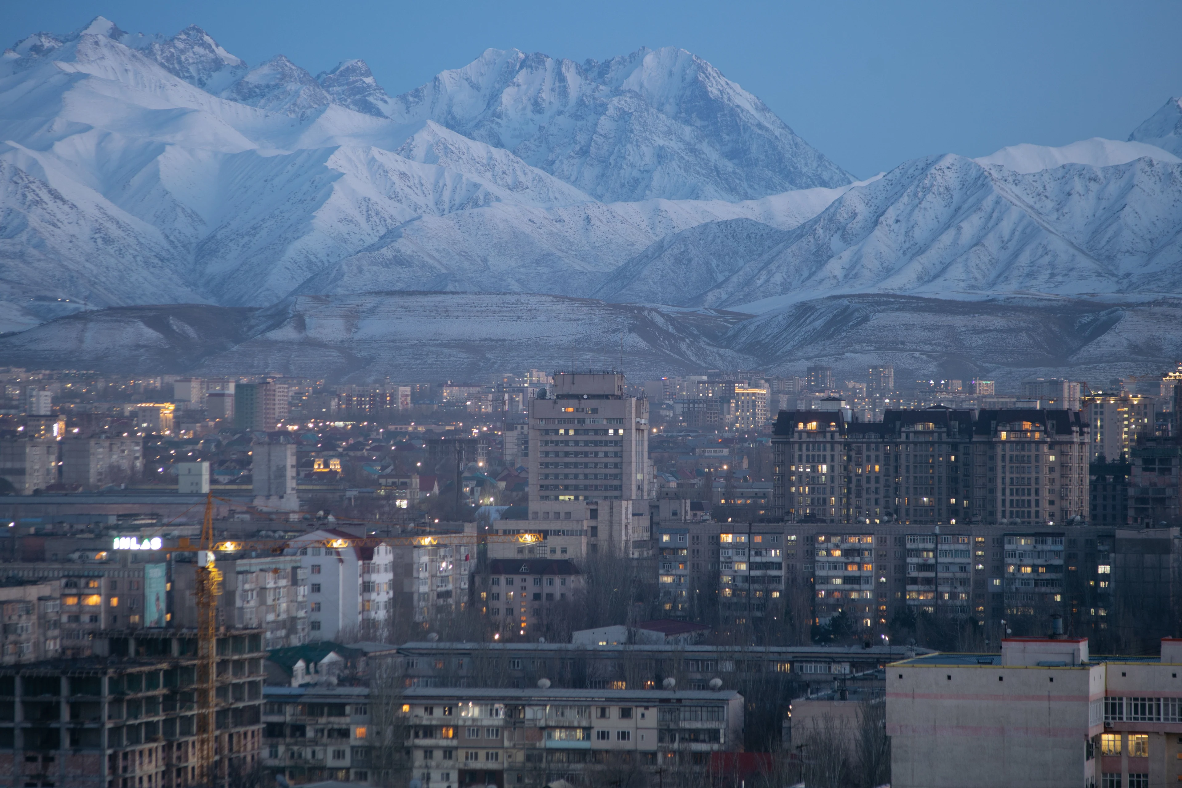Bishkek city and snow-covered mountains in the evening light.