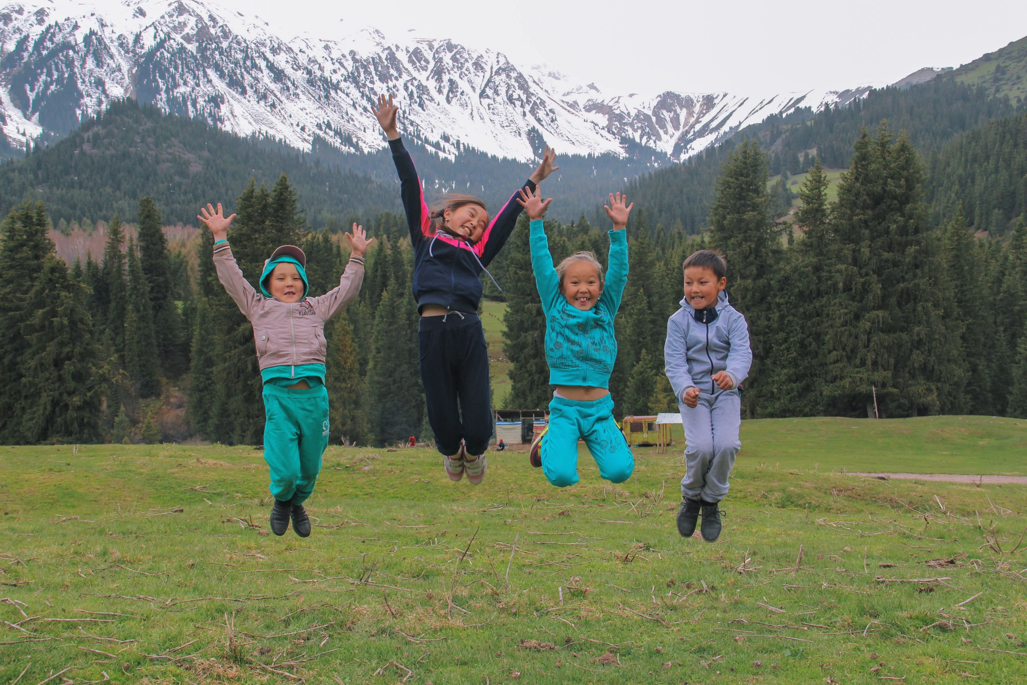 Four children jumping against a backdrop of mountains in Kyrgyzstan.