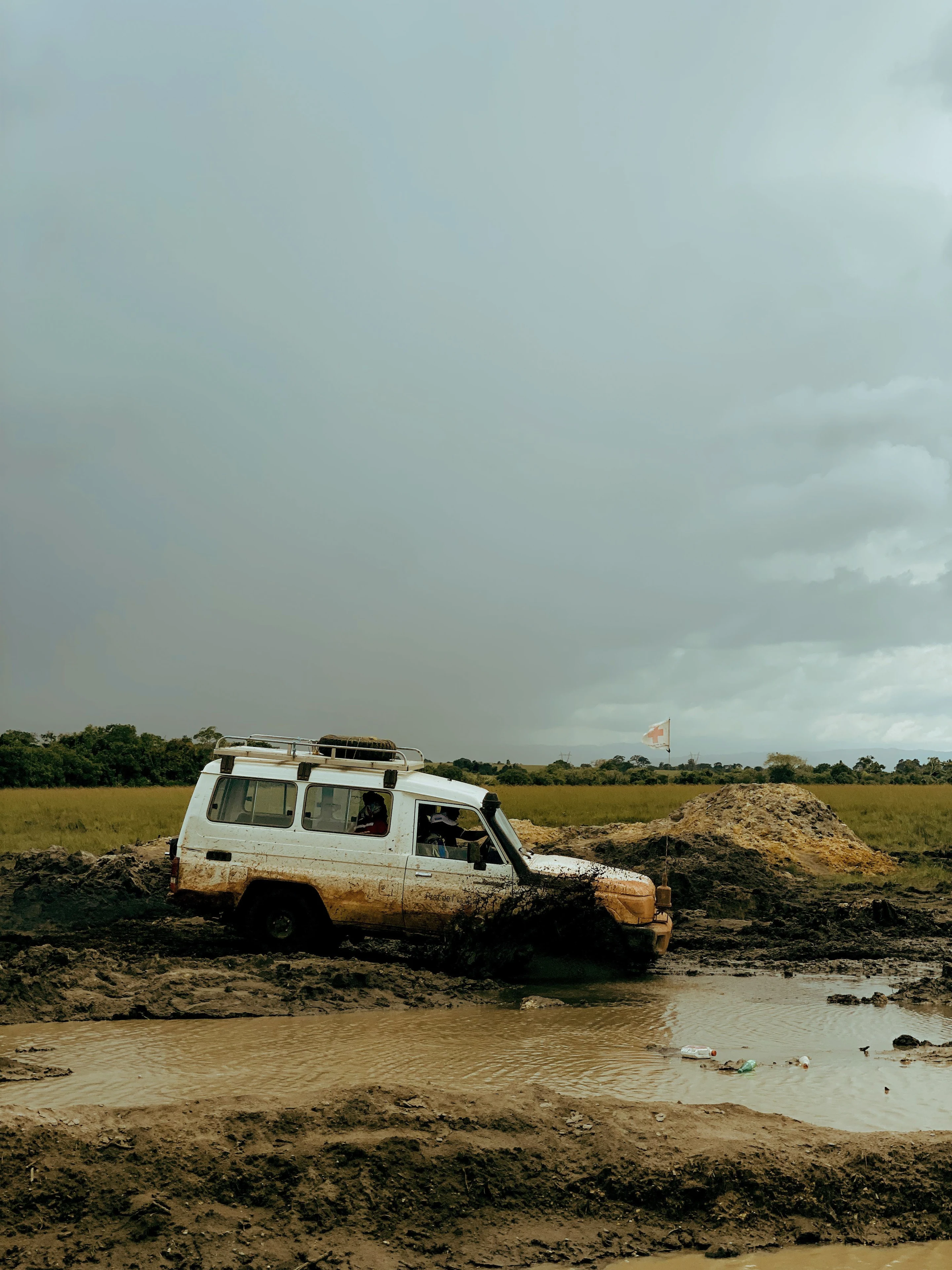A mud-covered four-wheel-drive vehicle crossing rough terrain.