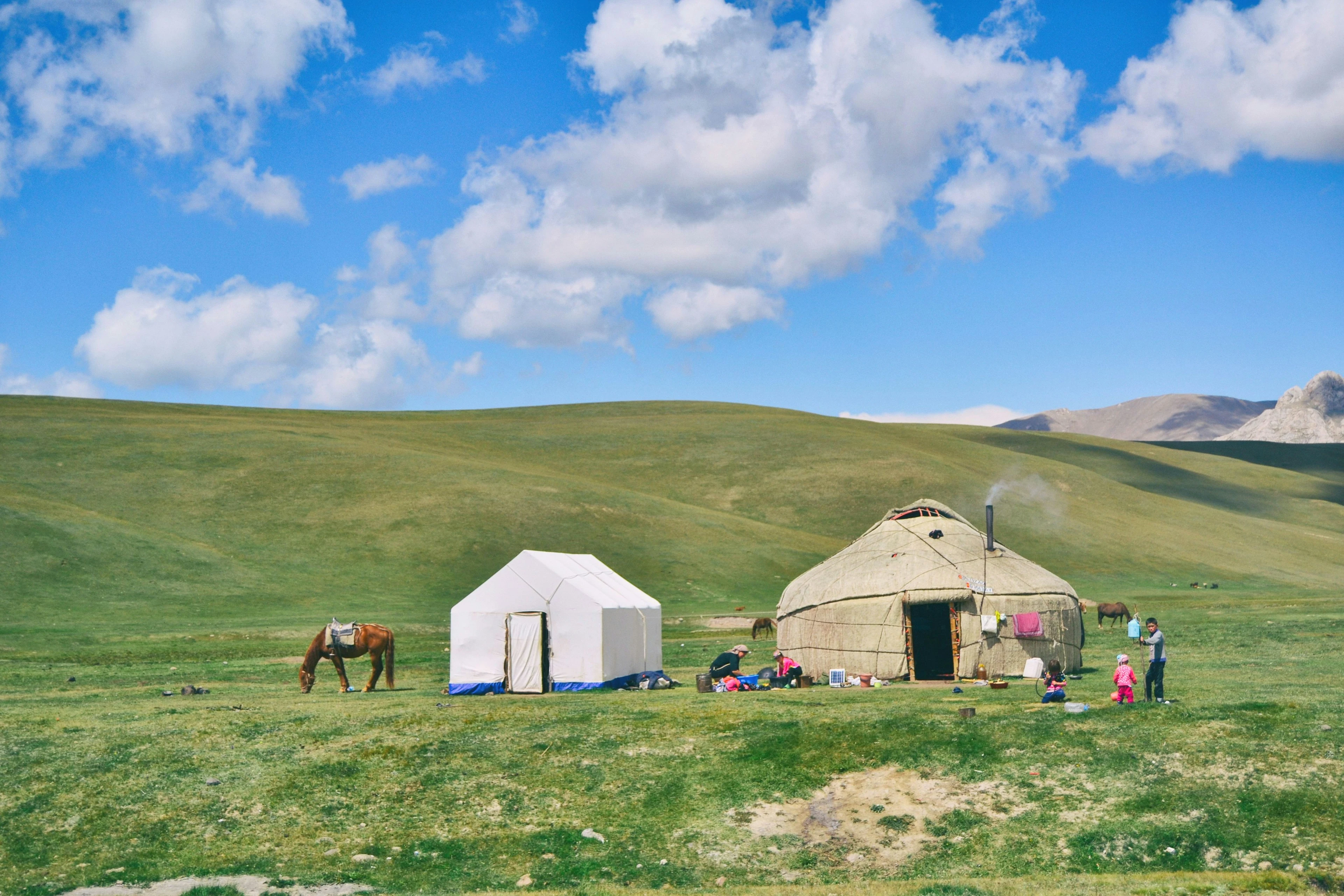 A family, a horse and yurts on the green summer pastures of Song-Kul.