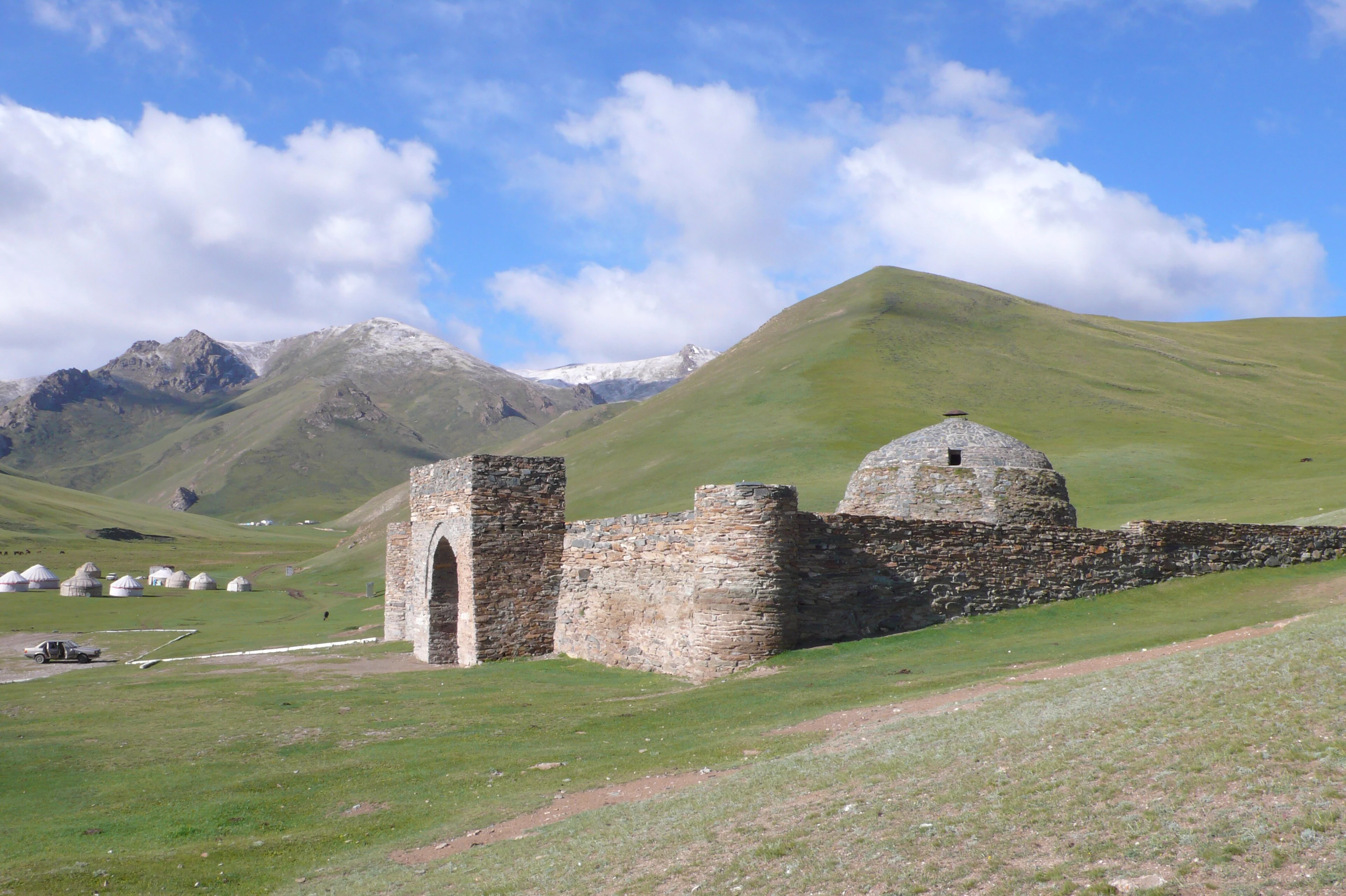 The stone walls and dome of Tash-Rabat caravanserai in its mountain valley.
